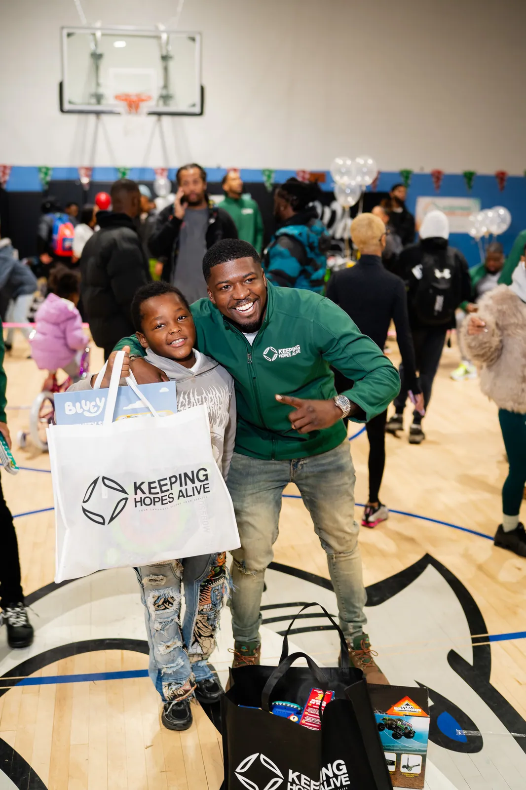 A KHA staff member and a child holding a Keeping Hopes Alive gift bag at the holiday drive