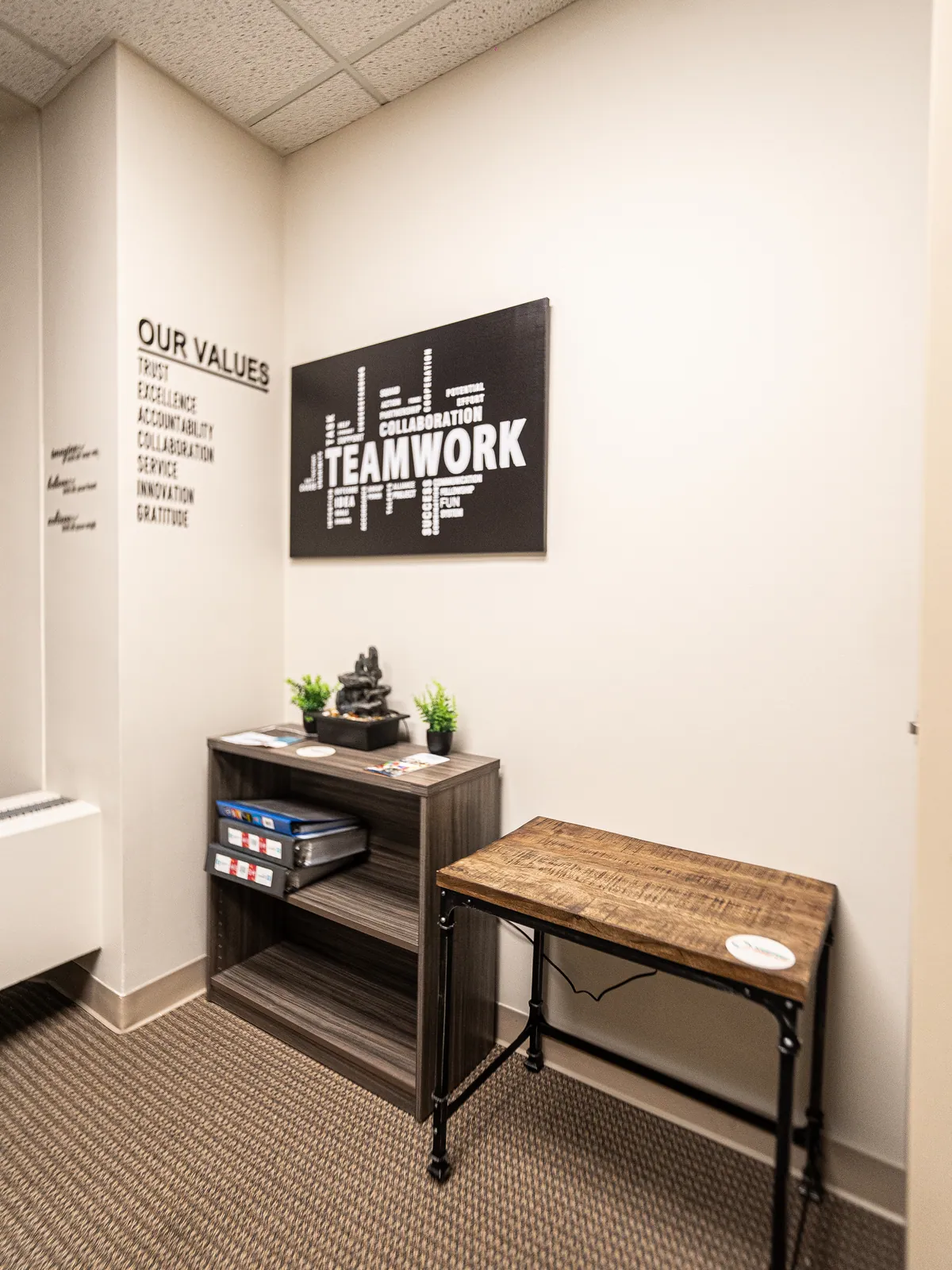 A quiet room at KHA with a values wall and a Teamwork sign above a small desk