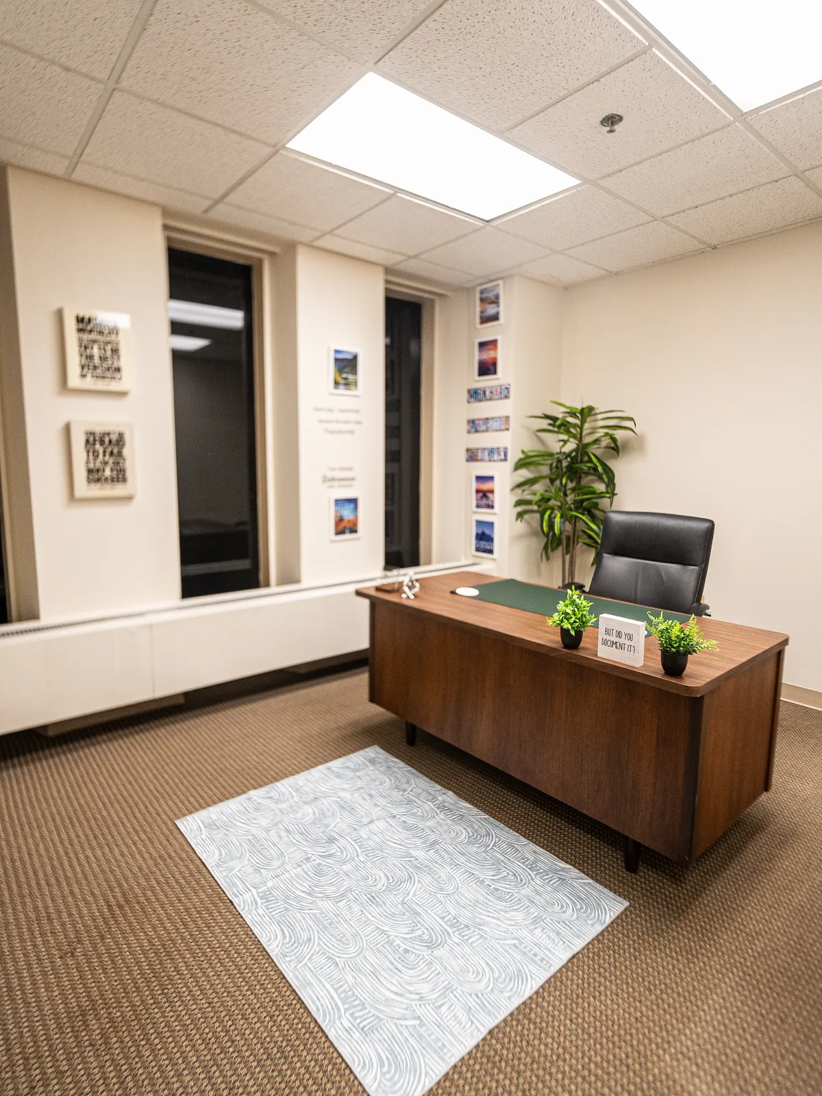 A calm therapist office with a wooden desk, plant and framed art