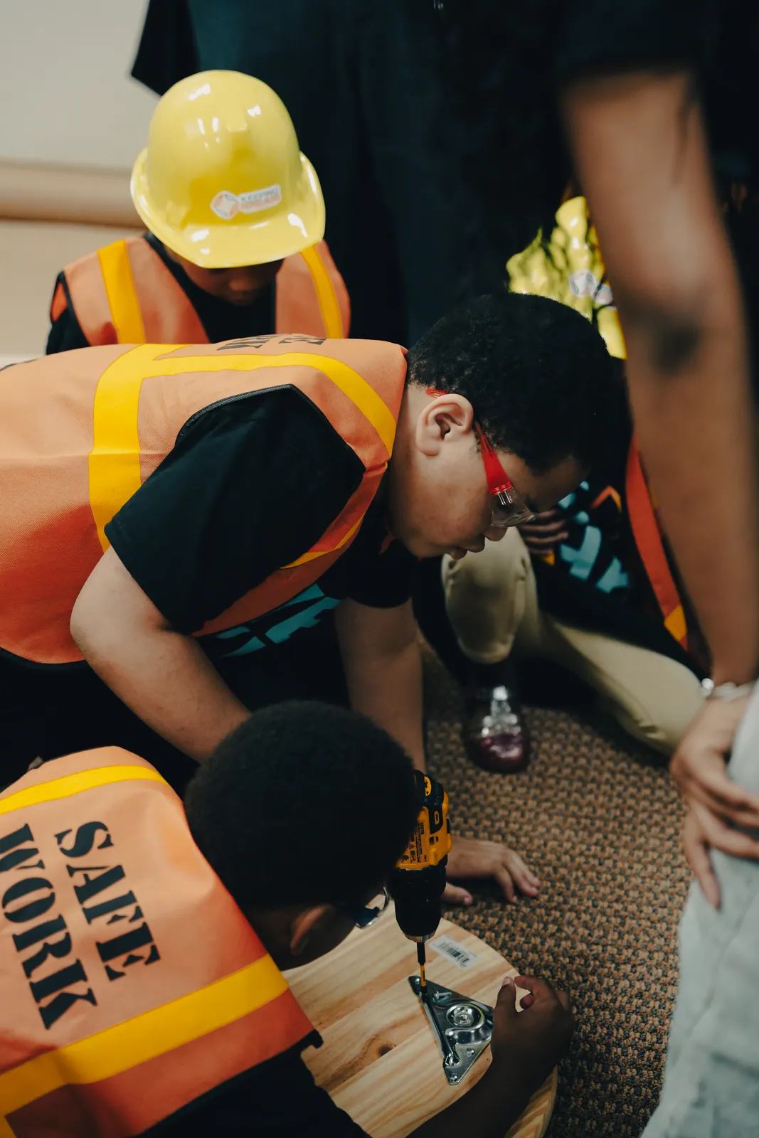 Youth in safety vests concentrating on a building task together