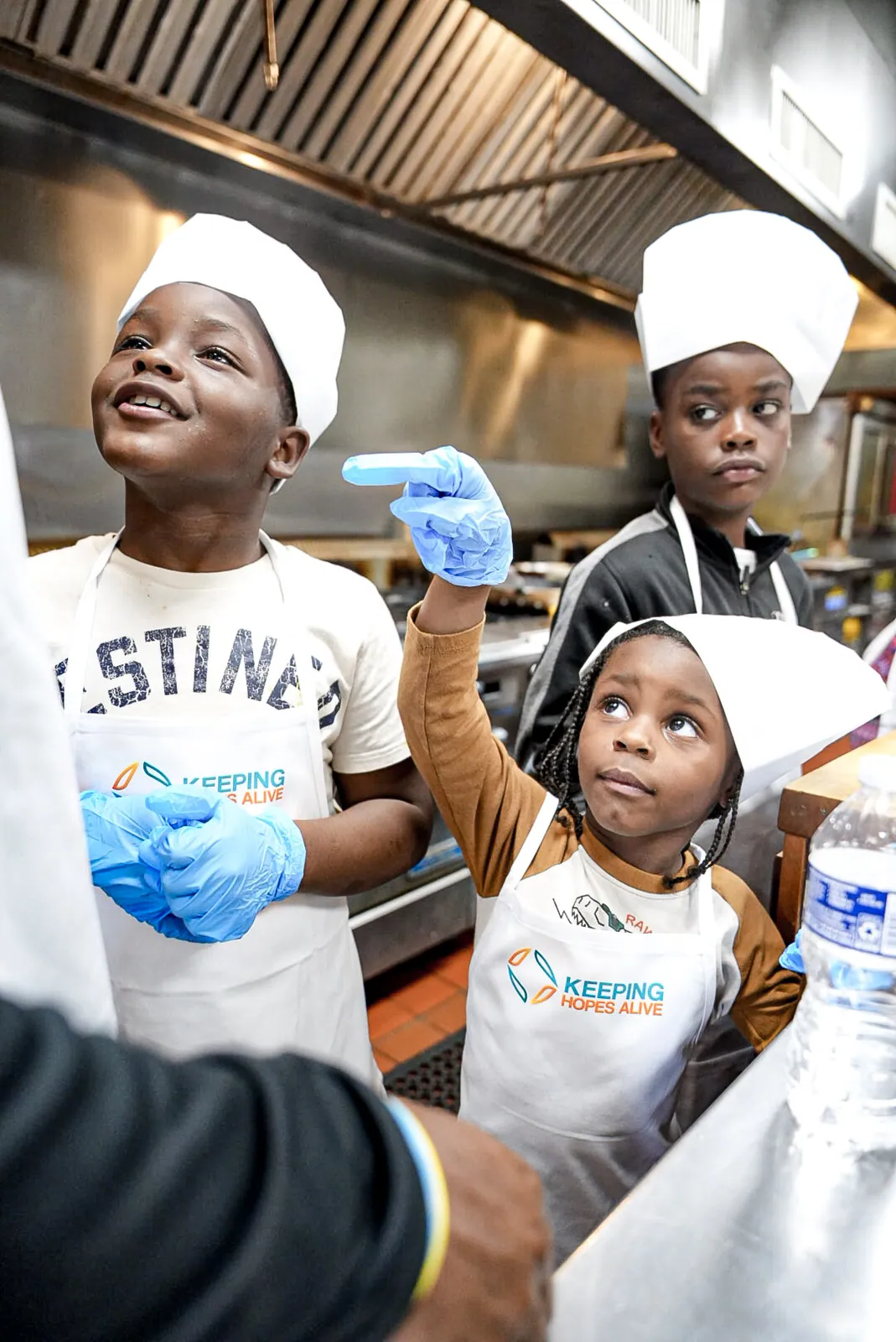 KHA youth in chef hats and aprons during a cooking class