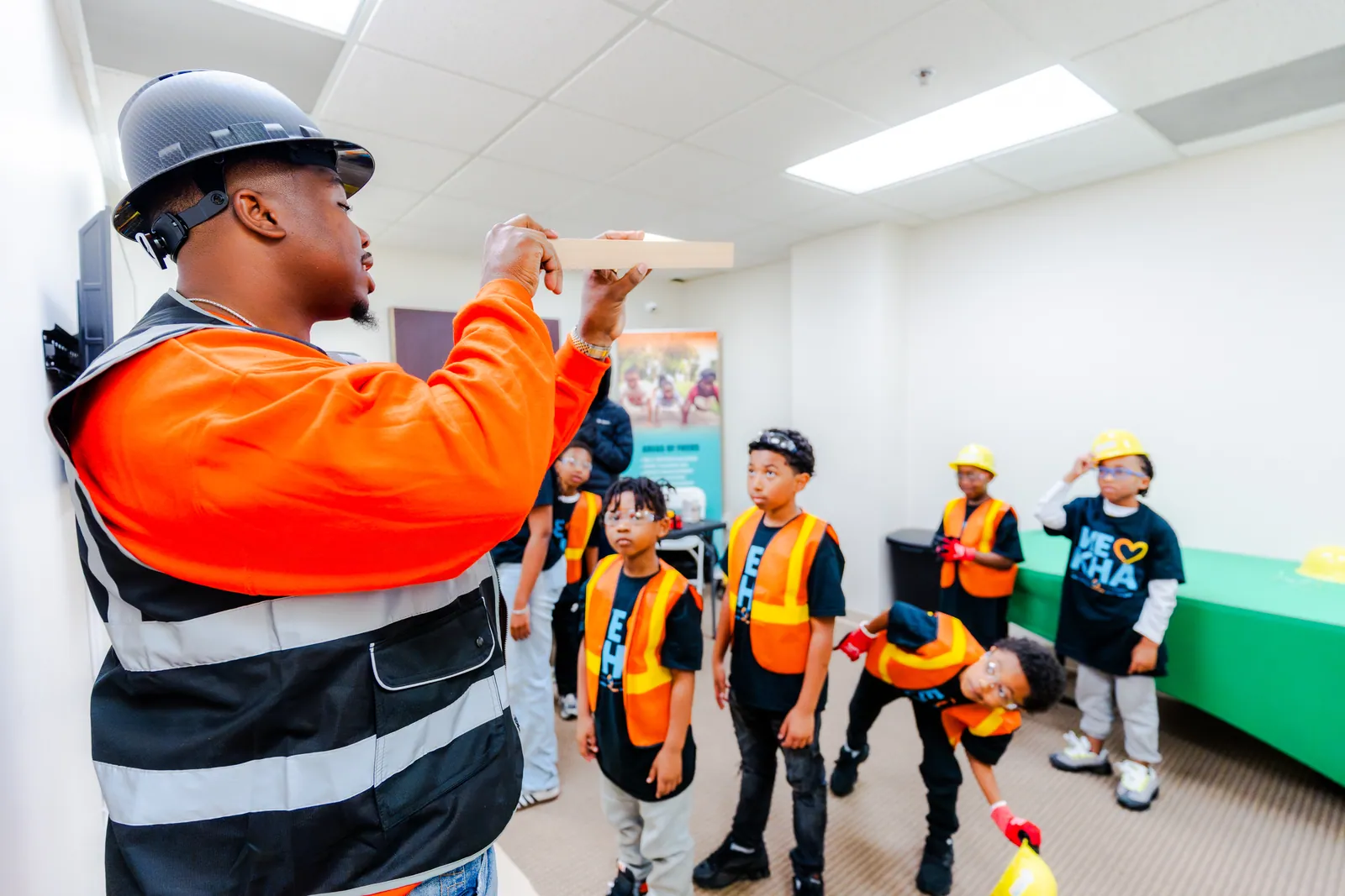 KHA youth listening to a construction mentor in safety gear