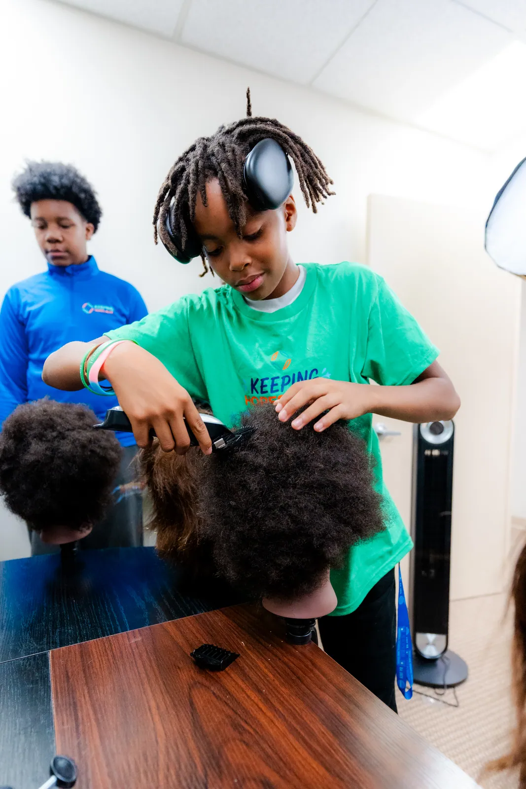 A young participant practicing barbering skills with focus