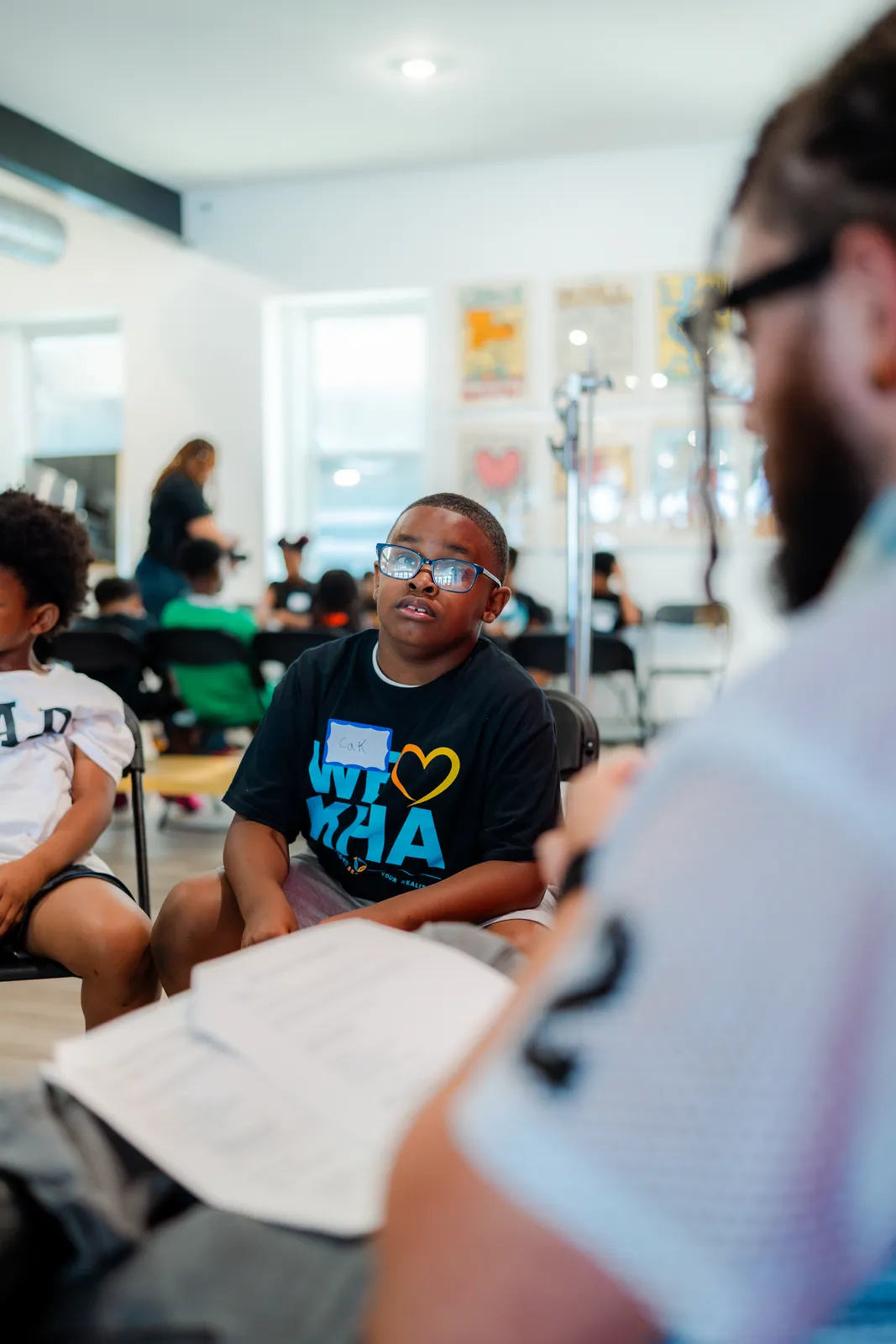 A KHA youth in a We Love KHA shirt reading a worksheet at DGTL University