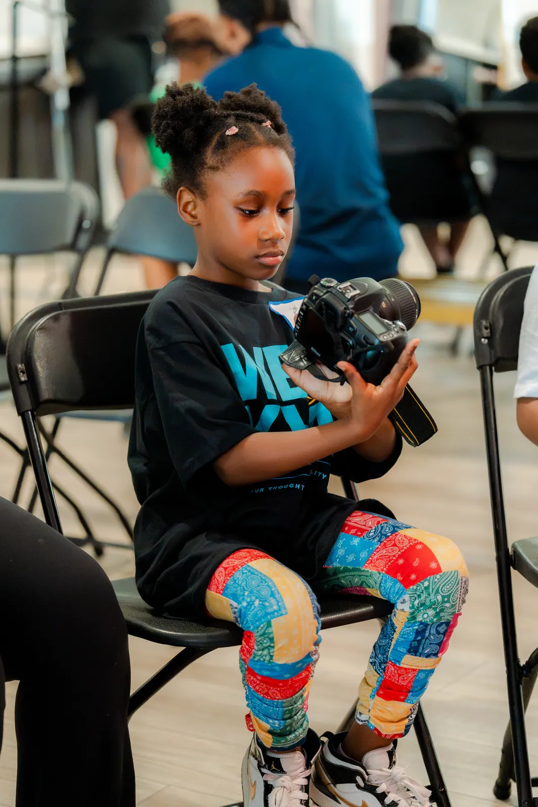 A young girl holding a camera at the DGTL University workshop