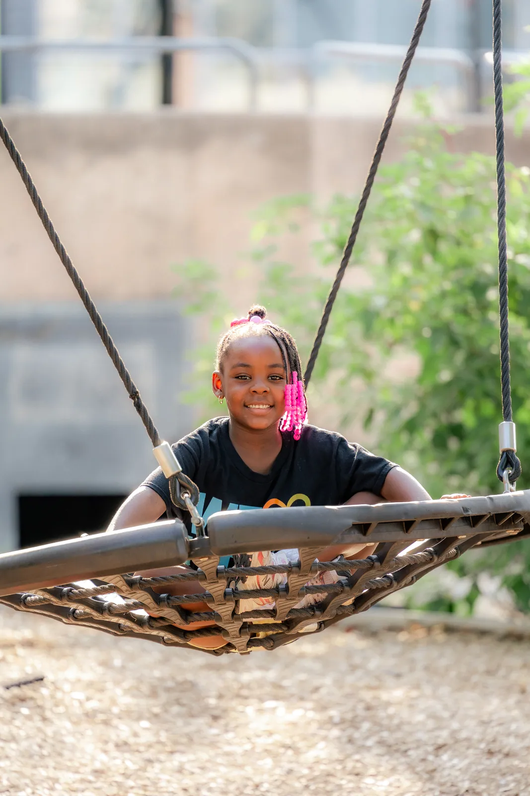A girl in a We Love KHA shirt relaxing on a swing