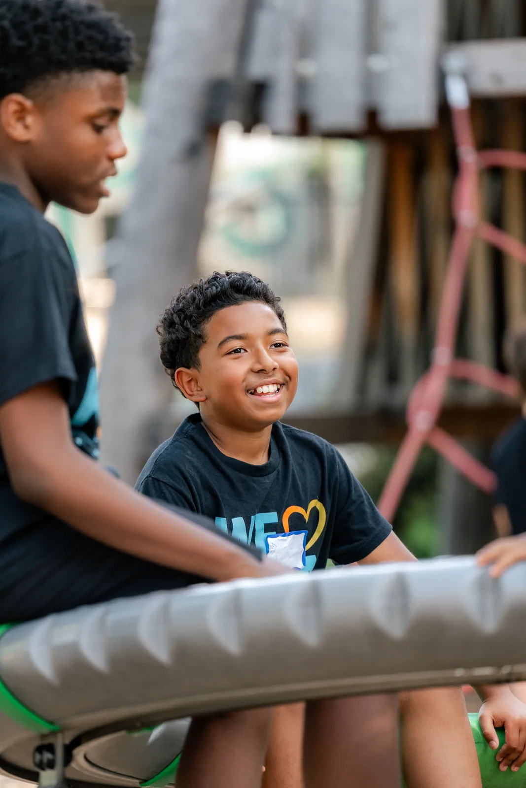 Two boys laughing together on outdoor play equipment