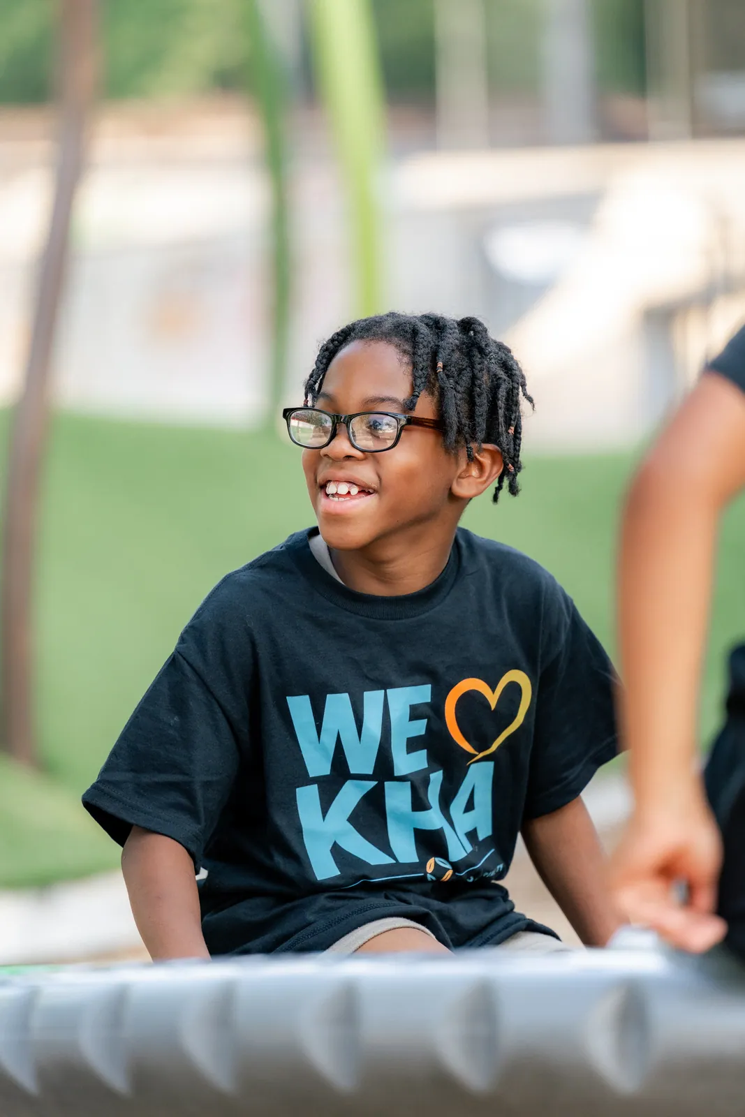 A smiling KHA youth in a We Love KHA shirt