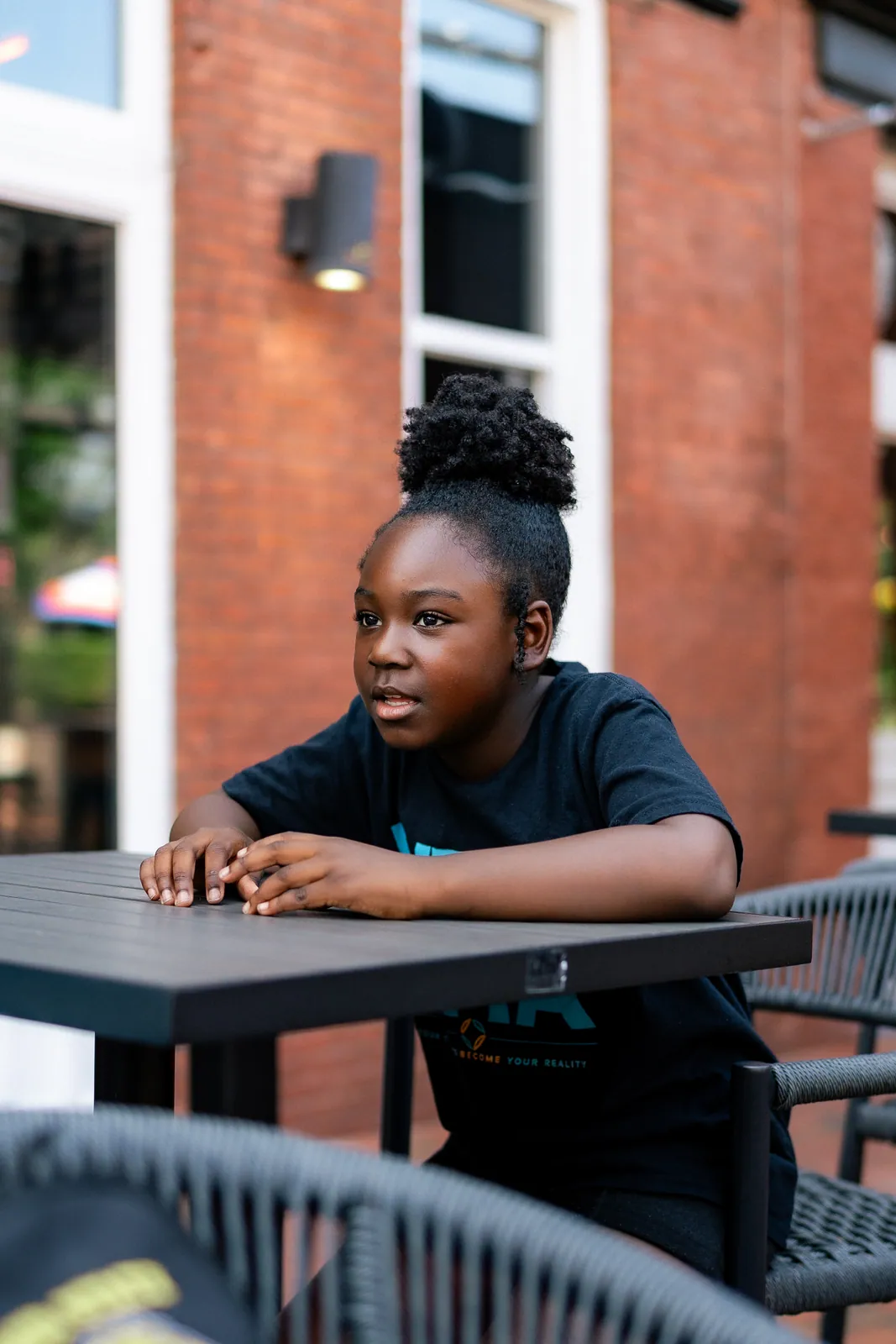 A young girl sitting at an outdoor table