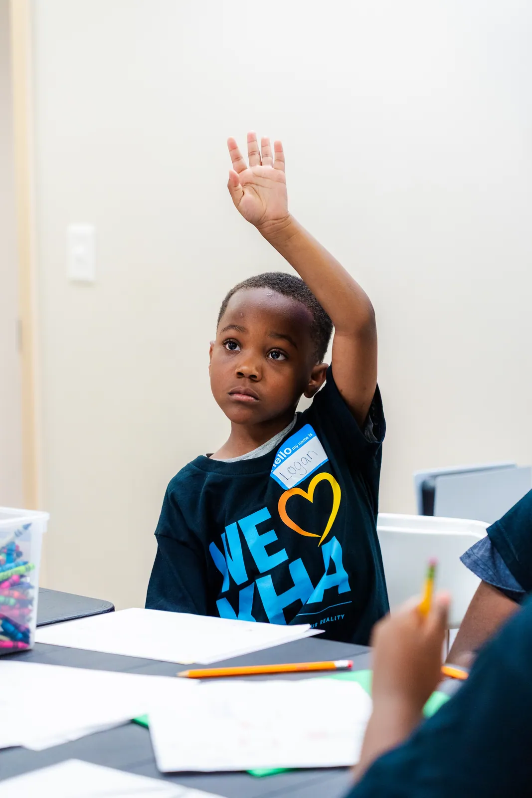A KHA youth raising his hand during a financial literacy workshop