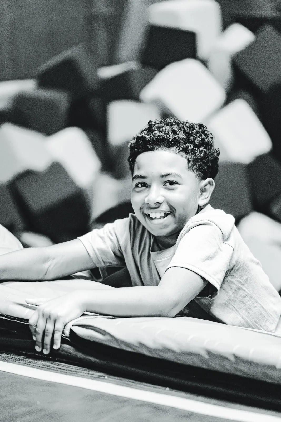 A smiling boy resting on the edge of the Sky Zone foam pit
