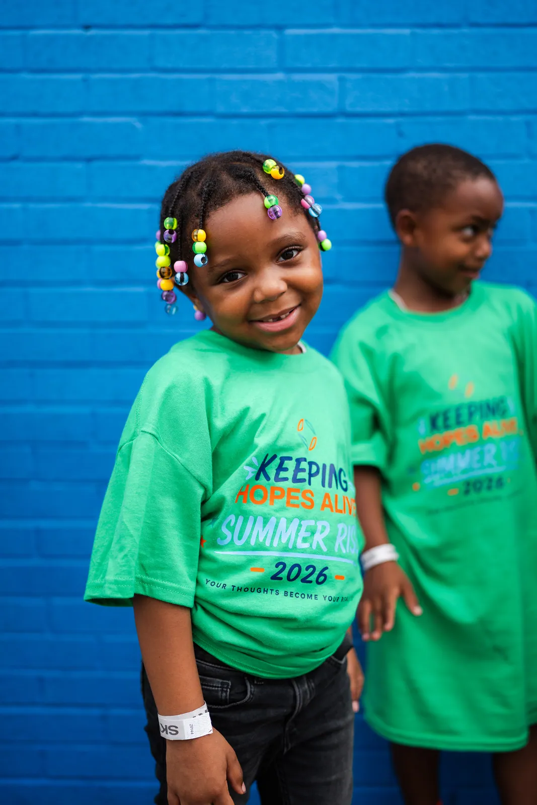 A smiling girl with beaded braids in a Summer RISE shirt