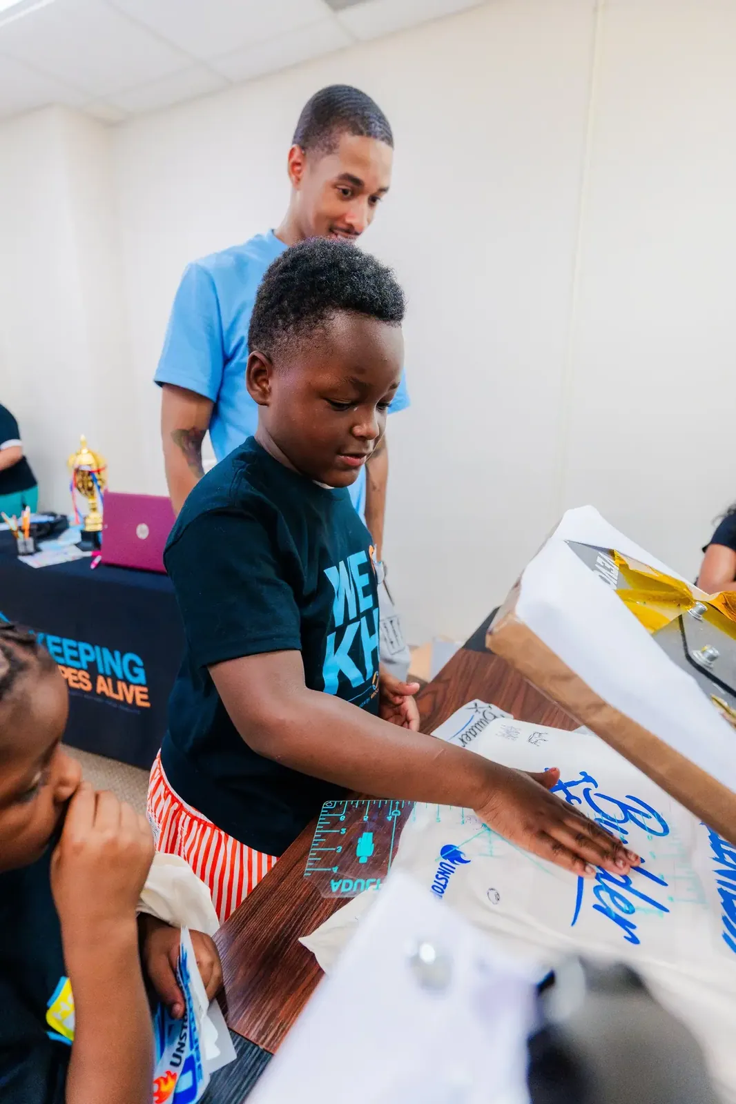 A mentor helping a boy design a t shirt