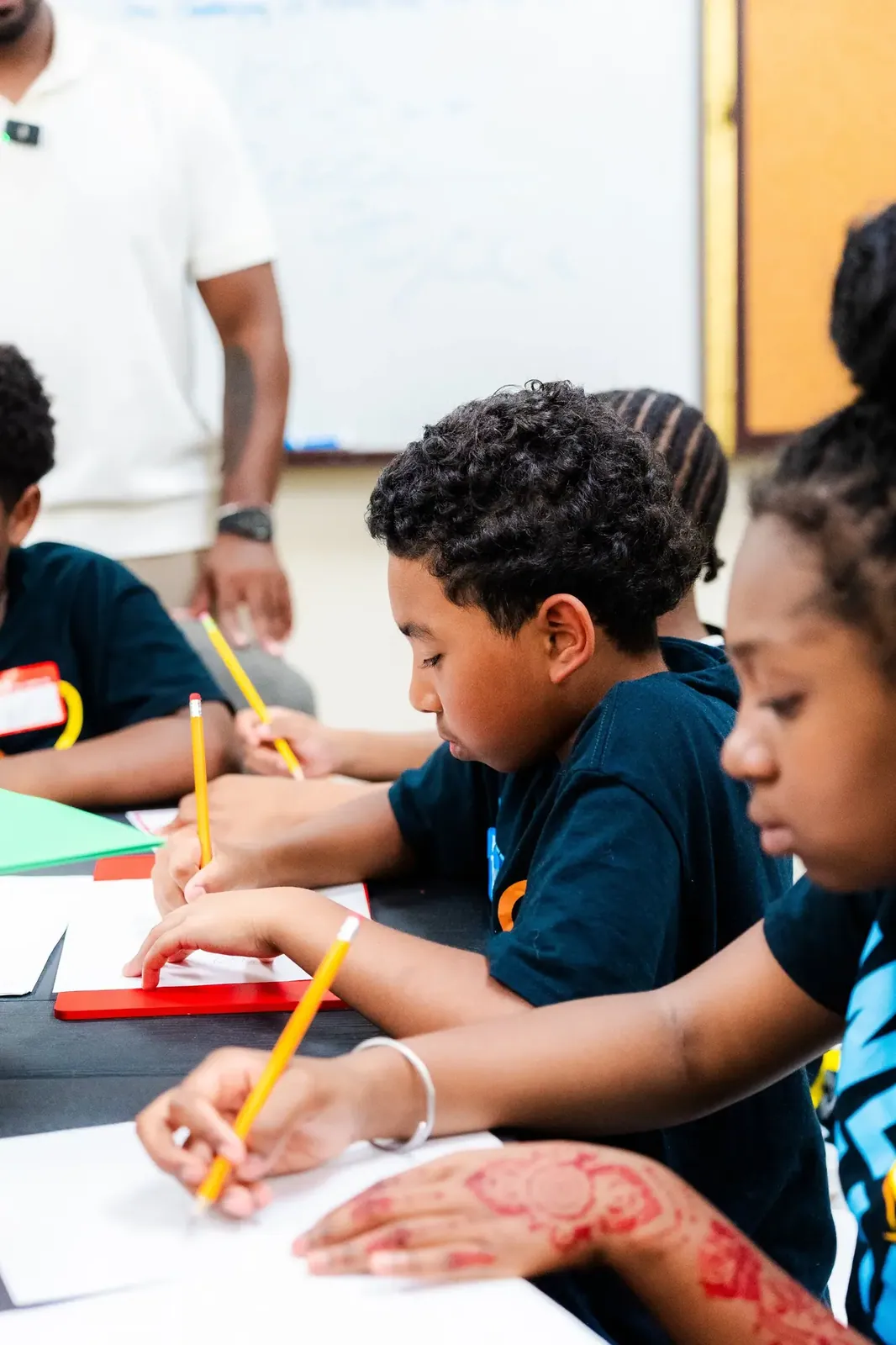 Kids writing together at a table during a KHA activity