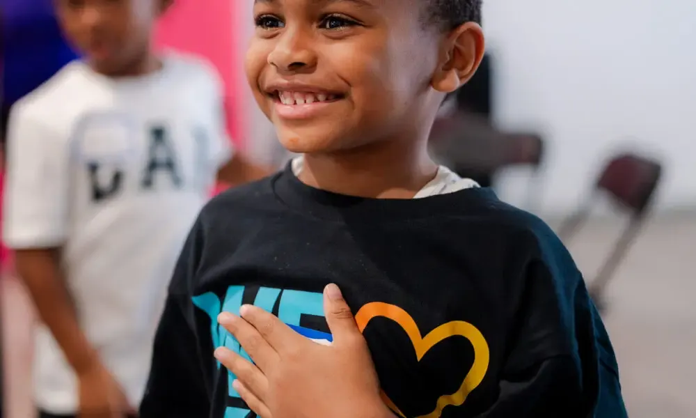 A smiling young participant in a We Love KHA shirt during Summer RISE
