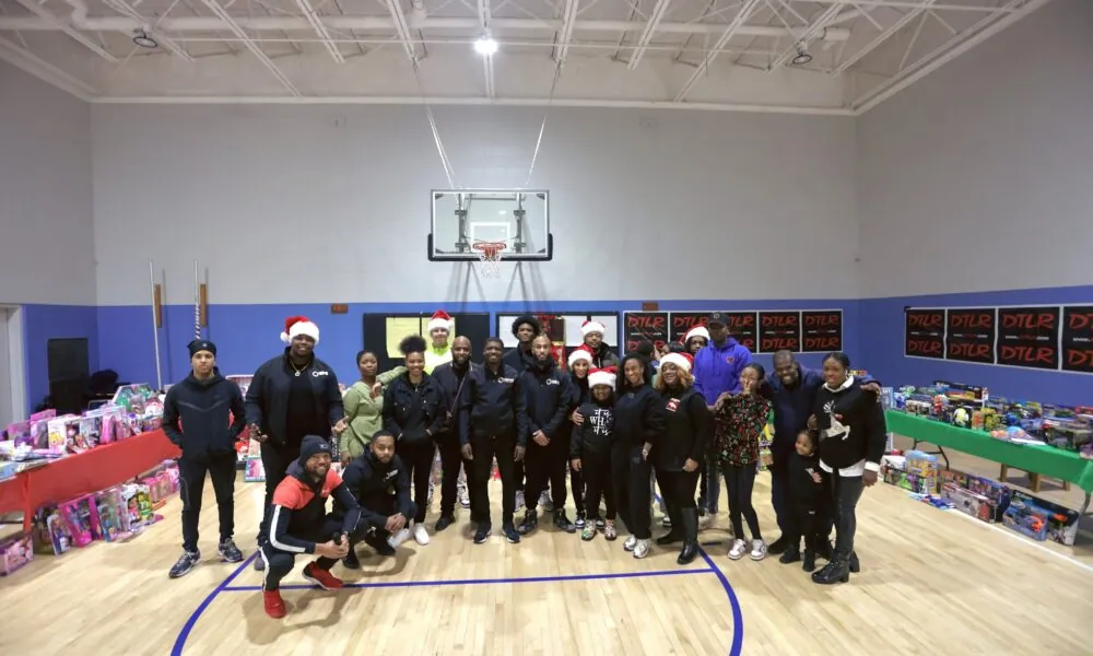 KHA staff and volunteers in Santa hats in a gym filled with toys